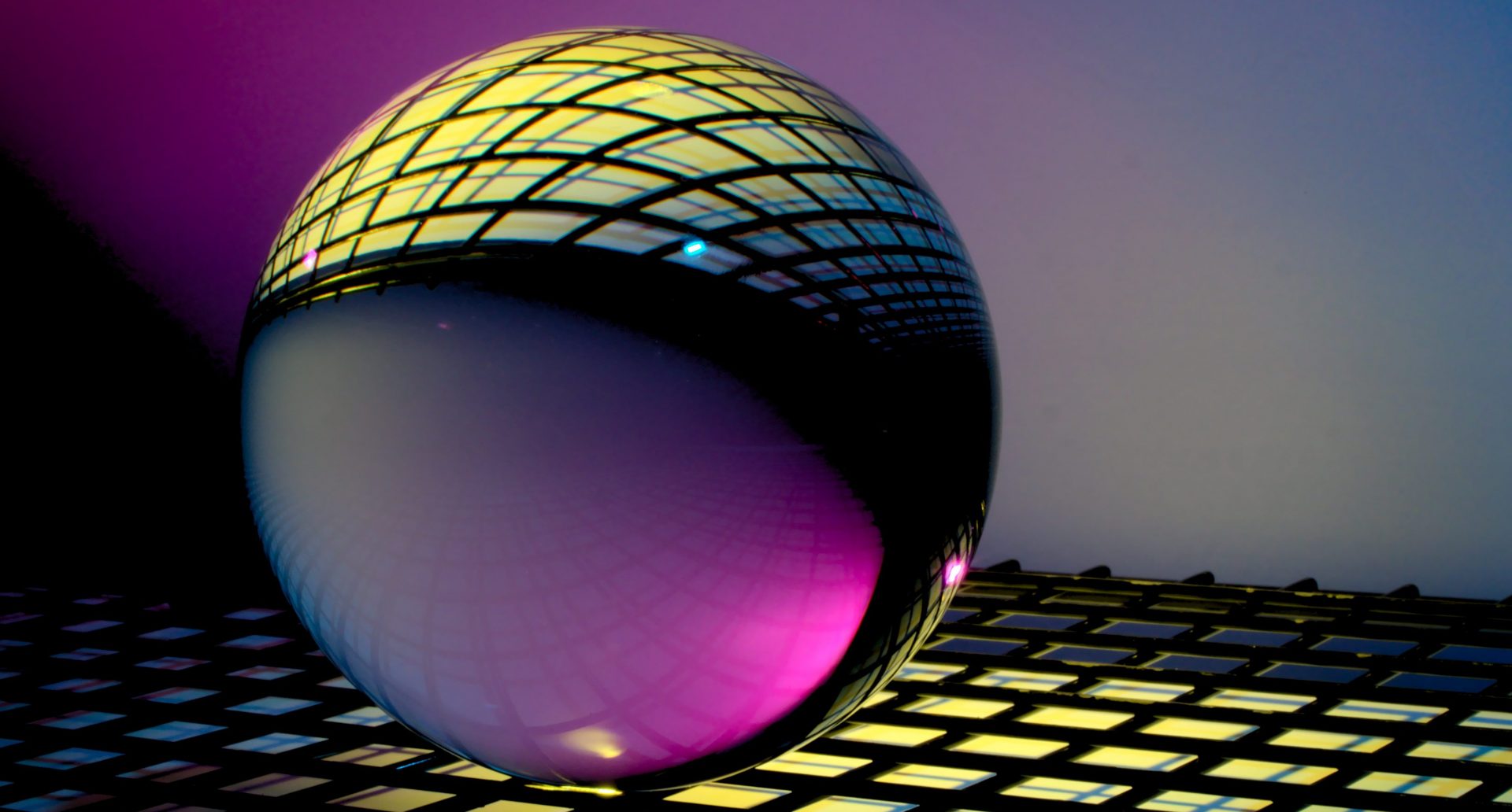 a cool sphere glass reflecting a yellow grid of metals in a dark background